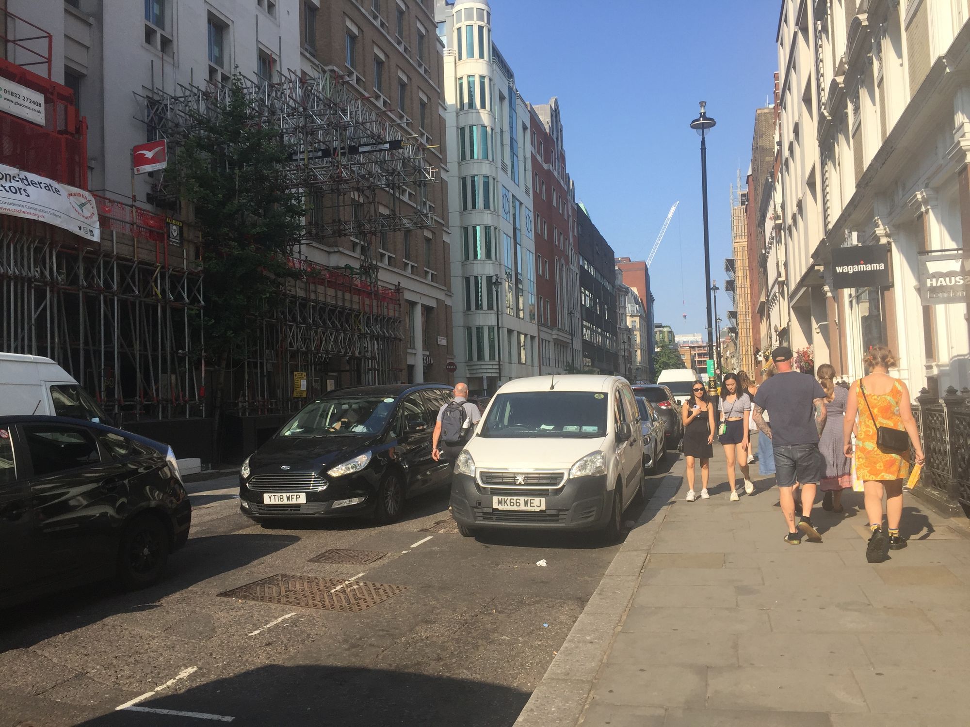 People walking and lots of vehicles on Great Malborough St, Soho